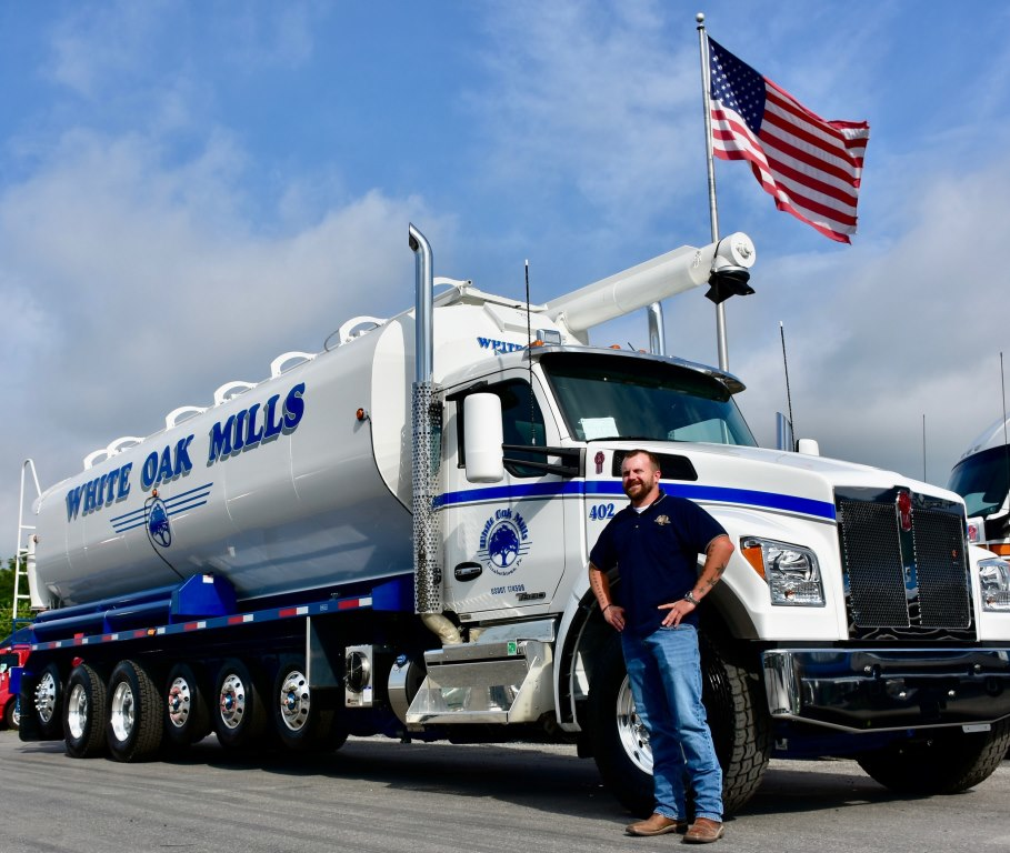 Josh Long White Oak Mills transportation manager stands beside a Kenworth T880S 7axle configuration with 26foot Walinga feed body
