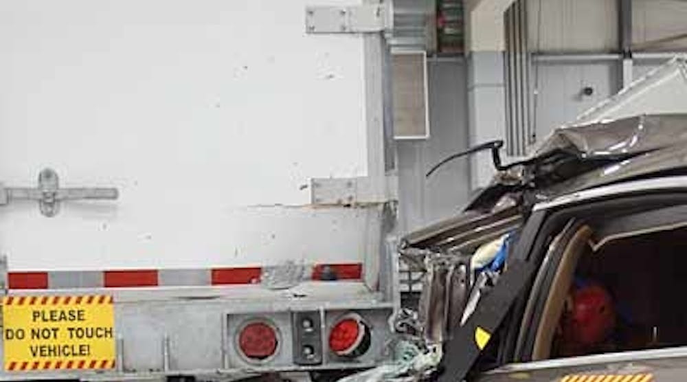 A Chevrolet Malibu is crashed into the rear of a Strick van trailer as part of the Insurance Institute for Highway Safety research program on underride guards. This crash involved striking only the outer edge of the crossbar. Guards proved effective in preventing underride as long as the automobile struck at least one of the vertical supports.