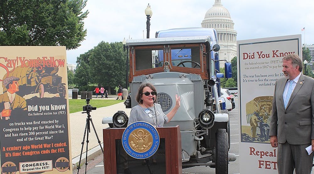 Jodie Teuton, chairwoman of the American Truck Dealers (ATD), explains opposition to the Federal Excise Tax. She stands in front of a Mack truck from the World War I era when FET was implemented. Rep. Doug LaMalfa looks on.