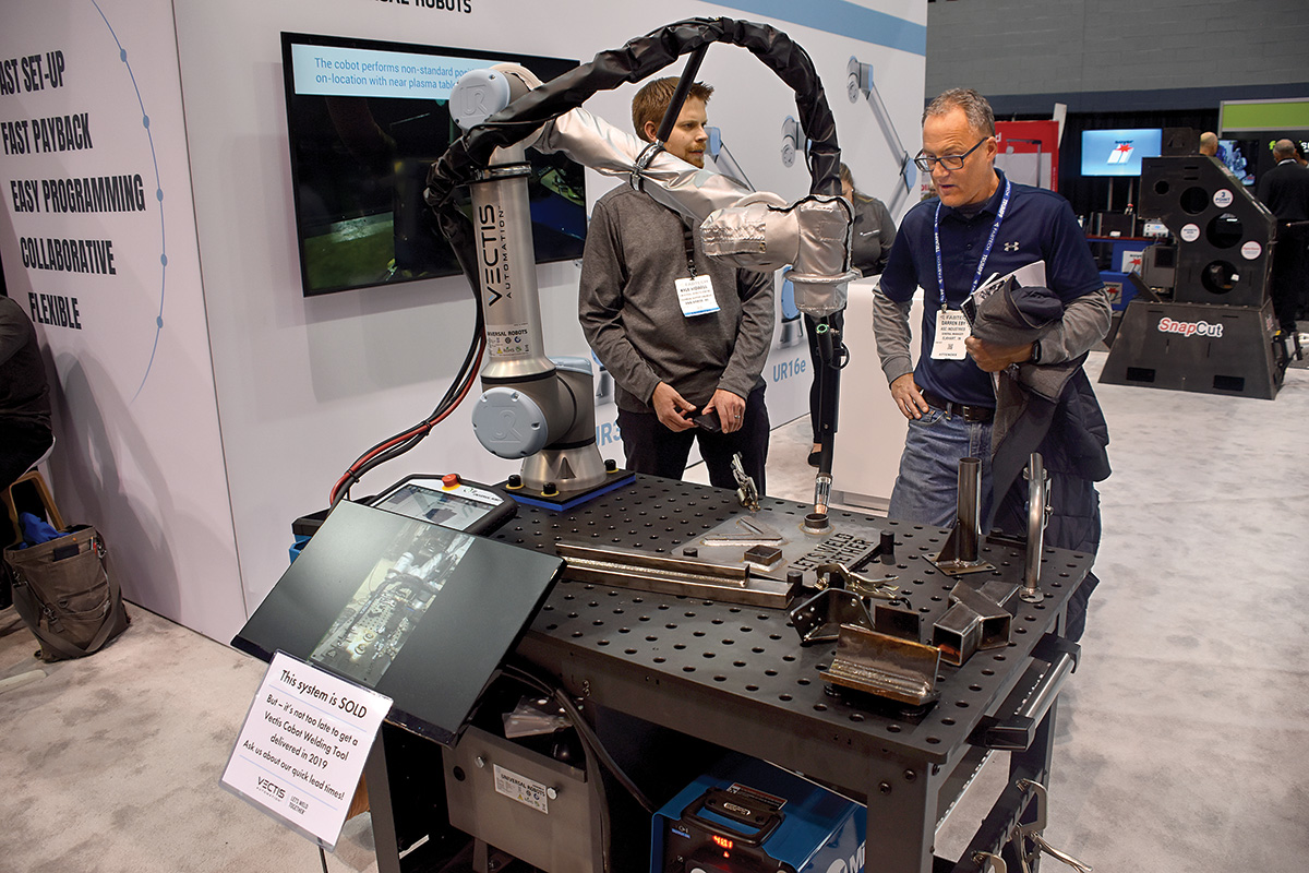 Vectis co-founder Josh Pawley, at left, explains the productivity advantages offered by a cobot welding system.
