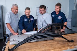EMCO engineers and workers reviewing specifications for 22.5K axle leaf springs at one of its Midwest locations. EMCO engineers and workers reviewing specifications for 22.5K axle leaf springs at one of its Midwest locations.