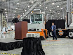 Kurt Neutgens addresses the crowd at Orange EV&rsquo;s new headquarters and factory in Kansas City, Kansas, as his co-founder Wayne Mathisen looks on.