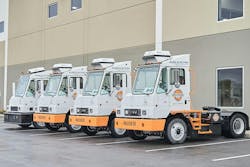 Orange EV electric terminal trucks lined up outside its new headquarters. Orange EV electric terminal trucks lined up outside its new headquarters.