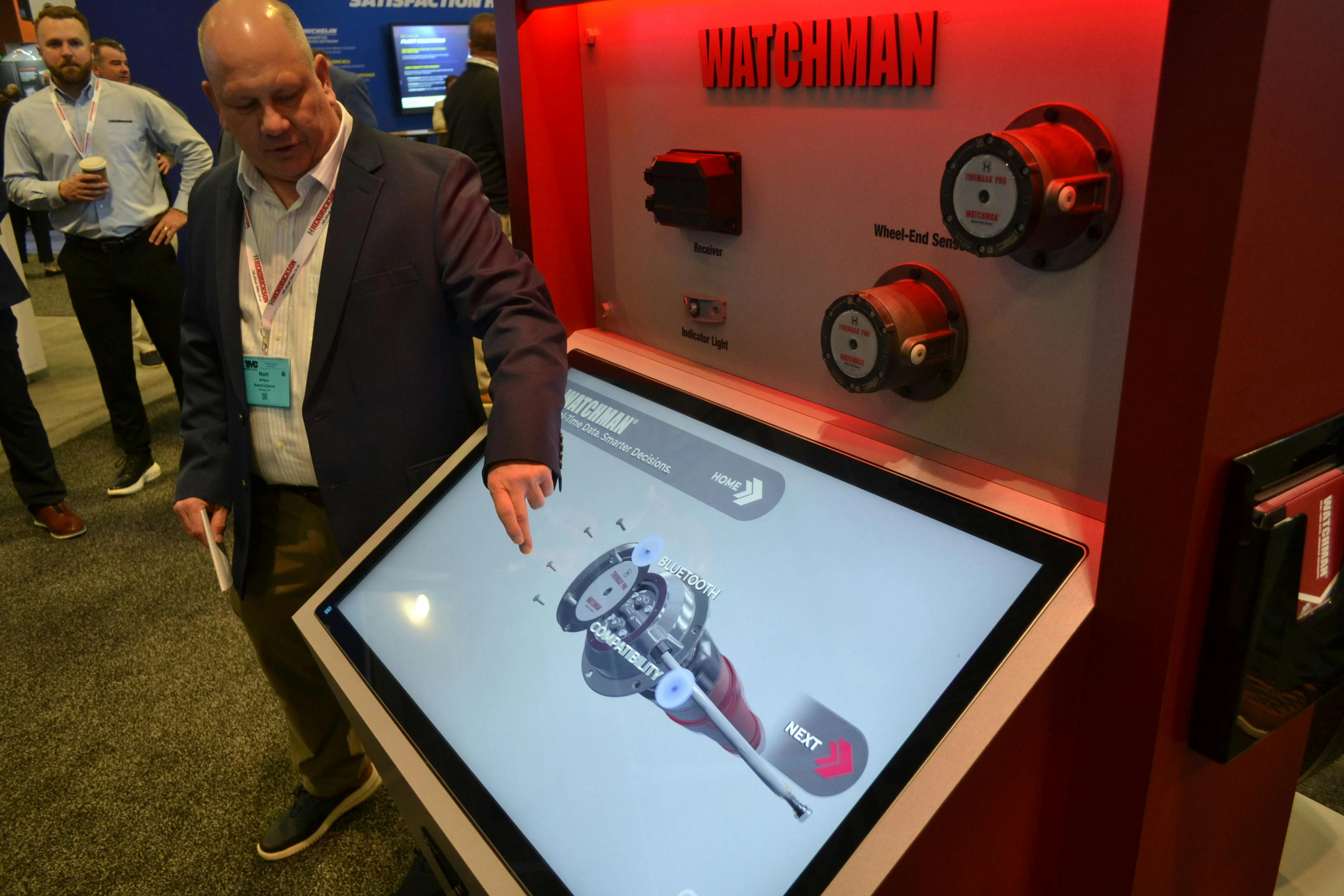 The WATCHMAN system combines Bluetooth hubcap‑mounted sensors, receiver, and the WATCHMAN mobile app to create a smart trailer wheel‑end insights platform, as Matt Wilson, VP of Hendrickson Vehicle Technology Group, explained at TMC.